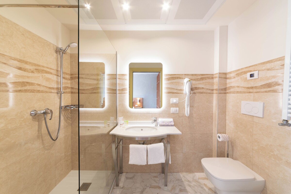 A modern bathroom with a glass-enclosed shower, a sink with a mirror above, and a toilet.