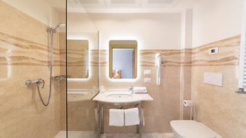 Une salle de bain moderne avec une douche à parois de verre, un lavabo avec un miroir au-dessus et des toilettes.
