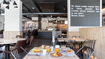 A restaurant with tables set for breakfast, including croissants and orange juice.
