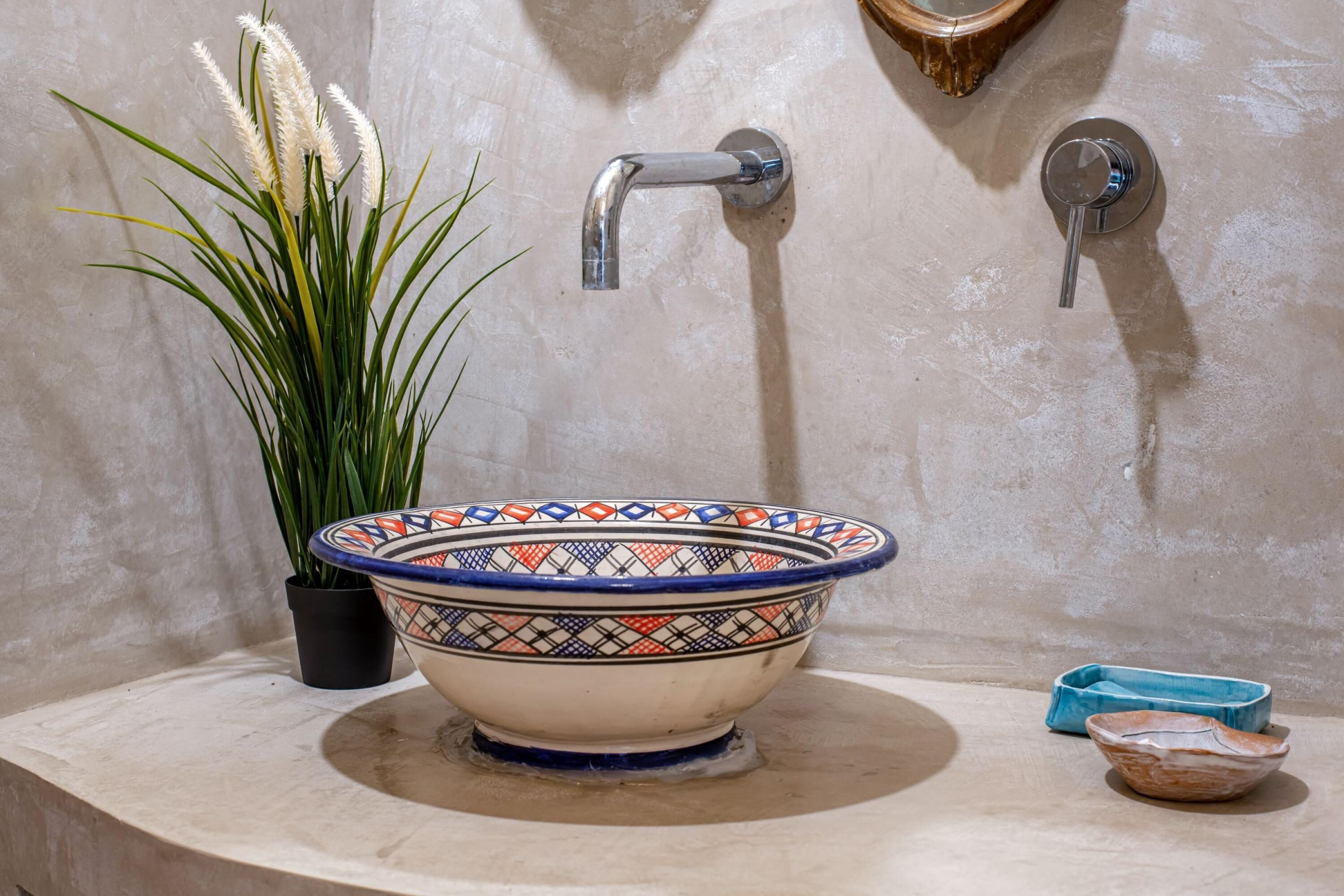 A bathroom with a decorative bowl sink, a potted plant, and a mirror.