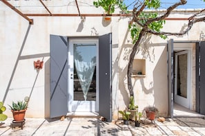Un bâtiment avec une porte ouverte, une petite plante et un cactus en pot.