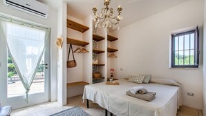 Une chambre à coucher avec un lit, un lustre, une fenêtre et des étagères intégrées.