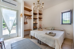 Een slaapkamer met een bed, een kroonluchter, een raam en inbouwplanken.