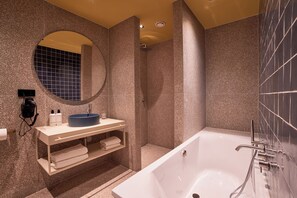 A modern bathroom with a freestanding bathtub, a round mirror, and a vanity with a sink and towel rack.