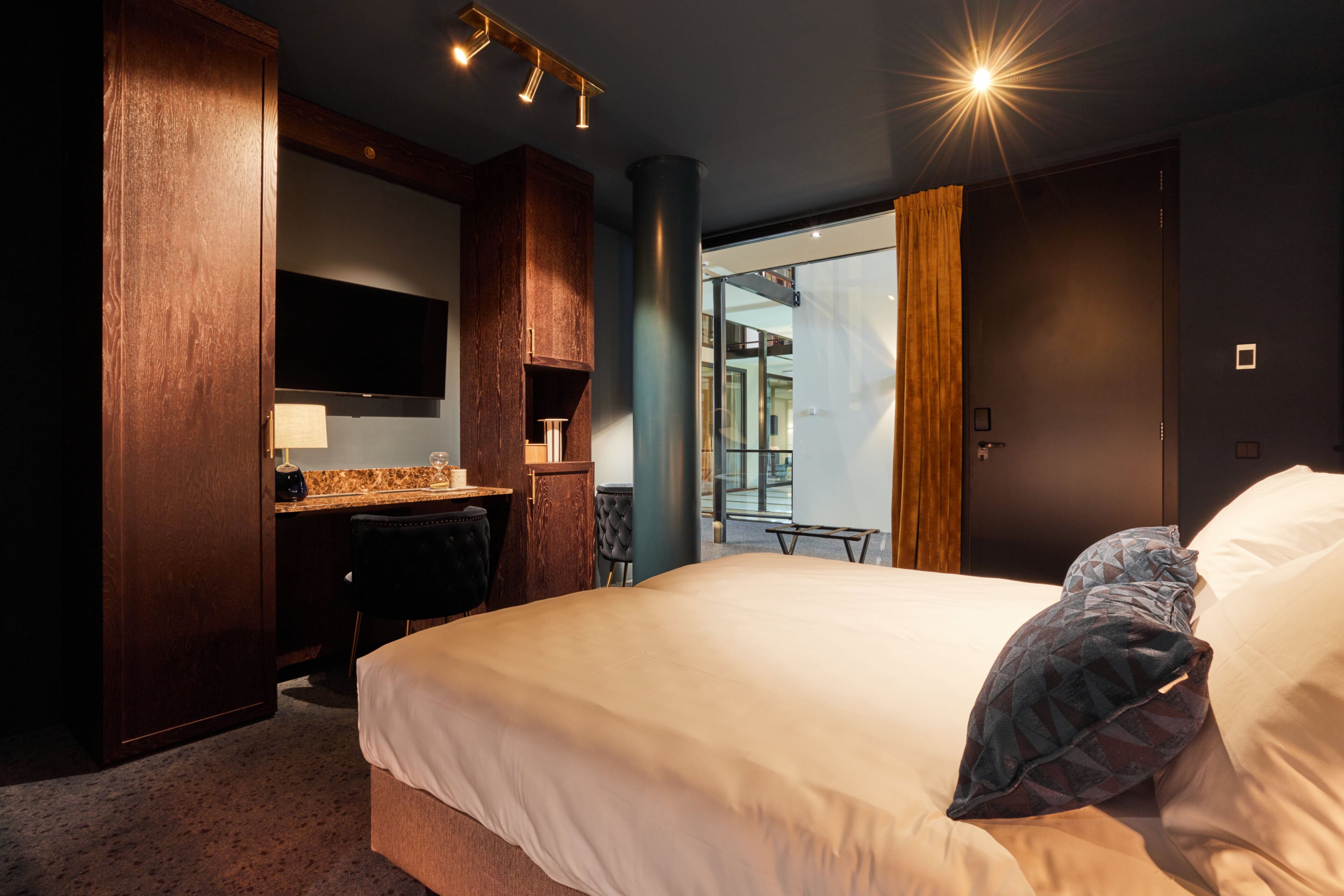 Ett hotellrum med en stor säng, ett skrivbord med en stol, en platt-TV och utsikt över omgivningarna.