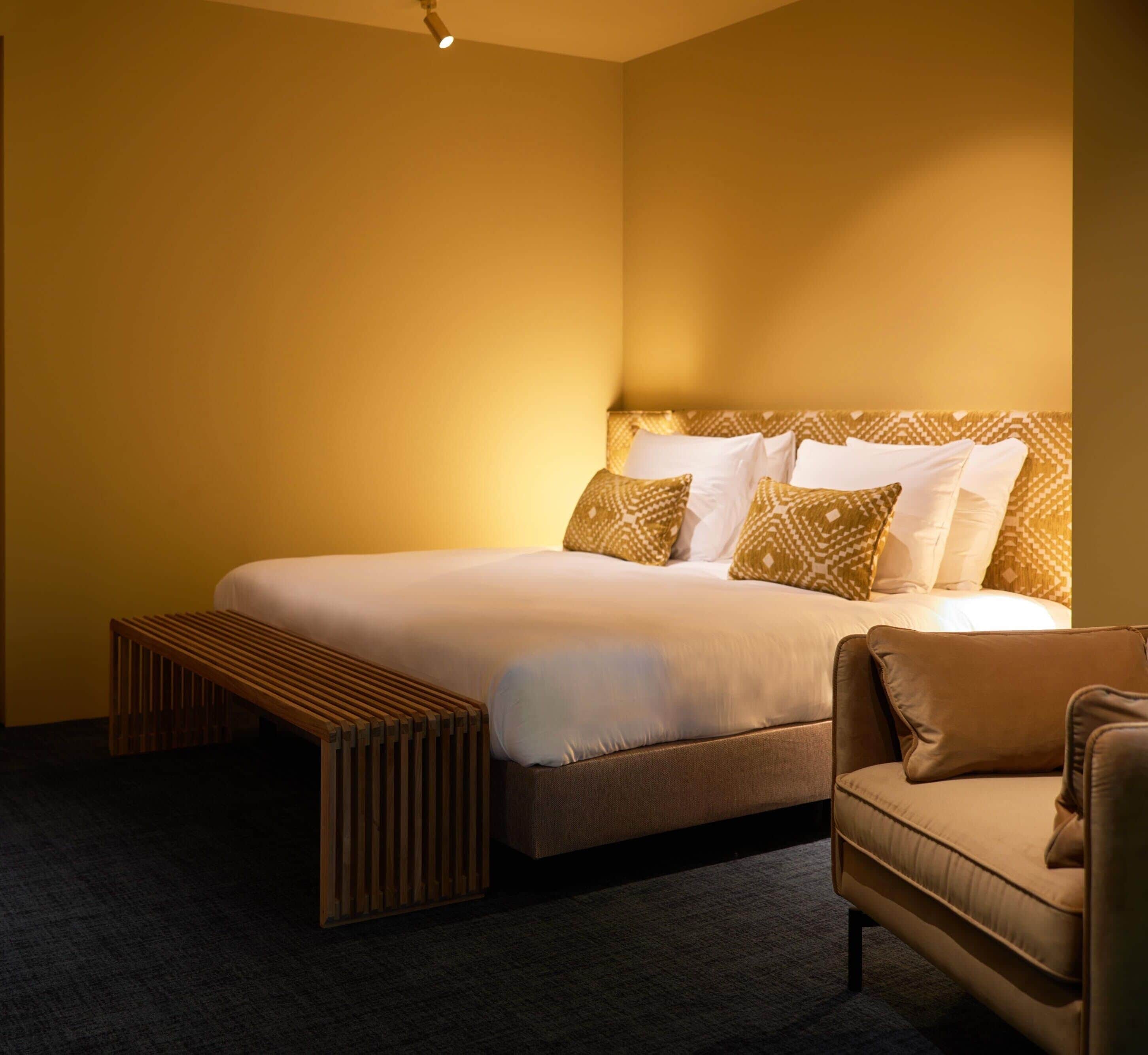 A hotel room with a bed, a bench, and a sofa.