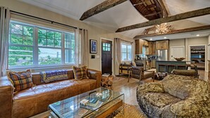 A spacious living room with a leather sofa, a glass coffee table, and a large furry rug. - The Wildcat's Lair: Renovated Home in Highlands w/ Private Deck, Smart Home Tech (Highlands)