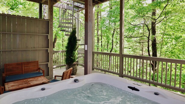 A hot tub with a wooden deck, a wooden bench, and a view of a forest. - The Wildcat's Lair: Renovated Home in Highlands w/ Private Deck, Smart Home Tech (Highlands)