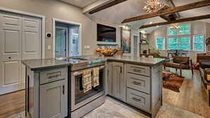 A modern kitchen with a central island, built-in oven, and a dining area with a chandelier. - The Wildcat's Lair: Renovated Home in Highlands w/ Private Deck, Smart Home Tech (Highlands)