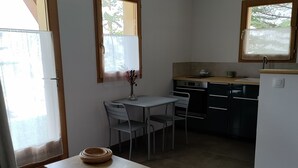 Une cuisine de taille réduite comprenant une table à manger, des chaises et un petit réfrigérateur.