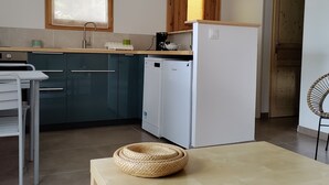 Une cuisine moderne avec des meubles de couleur bleu foncé, un réfrigérateur blanc et une fenêtre au-dessus de l’évier.
