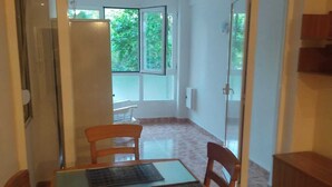 Un comedor con una mesa de vidrio, dos sillas y un armario de madera.