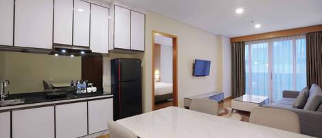 A modern hotel room with a kitchen, dining area, and a living space.
