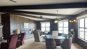 A cozy living room with a fireplace, comfortable seating, and large windows.