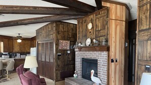 A cozy living room with a fireplace, wooden walls, and a comfortable seating area.