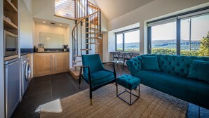A modern kitchen with a built-in washing machine, a teal sofa, and a spiral staircase. - The Byre, Waternish, Isle of Skye - Luxury Self Catering (Isle of Skye)
