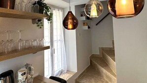 Cocina moderna con estantes de madera, lámparas colgantes y una escalera que sube a otro nivel.