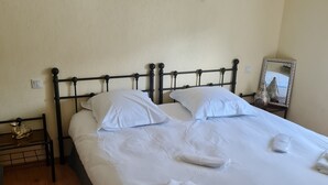 Ein ordentlich bezogenes Bett mit weißen Leinen, einem Metall-Kopfteil und einem Nachttisch mit einer kleinen Dekoration.