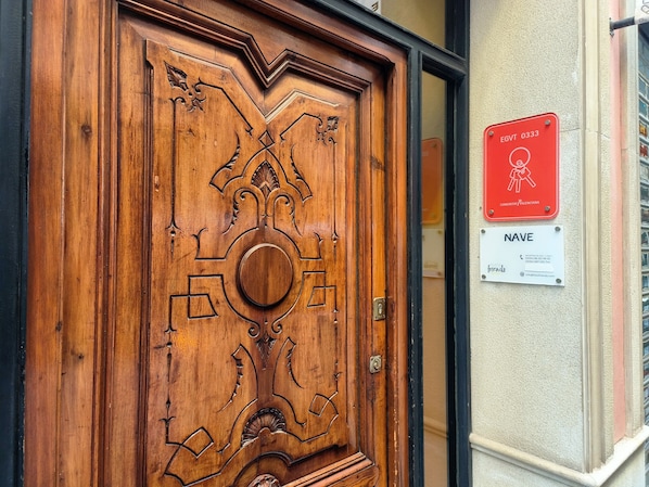 A wooden door with intricate carvings, a red sign with a figure and text, and a white sign with contact information. - Flats Friends Nave 1  bedroom with terrace (Valencia)