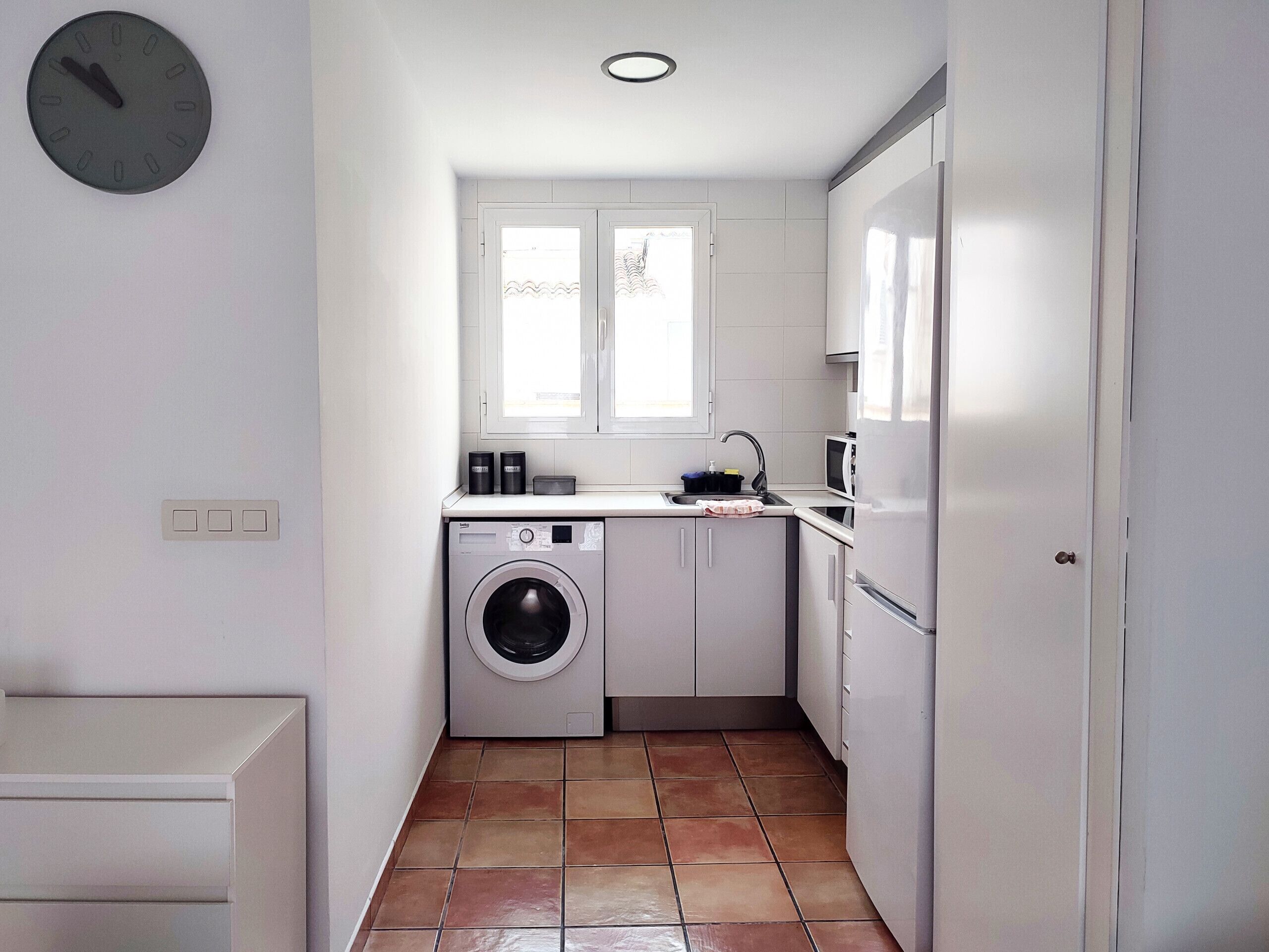Une cuisine compacte équipée d’un lave-linge, d’un four à micro-ondes et d’un évier.