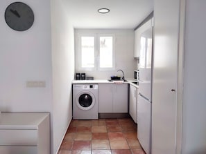 A compact kitchen with a washing machine, a microwave, and a sink.