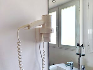 A hair dryer mounted on a wall in a bathroom with a window and a sink. - Flats Friends Nave 1  bedroom with terrace (Valencia)
