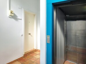 A hallway with a white door and a blue wall, leading to an elevator.