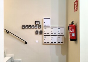 Un système d’alarme incendie fixé au mur, un extincteur et un ensemble d’interphones.