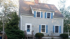 A two-story house with a front porch, a chimney, and a well-maintained lawn. - Oak Bluffs Rental - Walk to the Beach (Oak Bluffs)