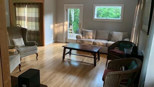 A living room with a sofa set, a coffee table, and a chair. There are two windows providing natural light. - Oak Bluffs Rental - Walk to the Beach (Oak Bluffs)