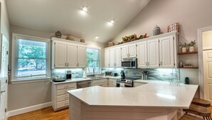 Una cocina moderna con armarios blancos, una isla grande y electrodomésticos integrados.