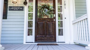Una puerta de madera con un panel de vidrio, un letrero que dice 'The Young Family Lakehouse EST. 2020' y el número '101' en la pared.