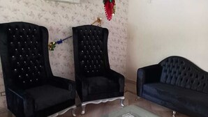 A living room with two black upholstered chairs, a glass coffee table, and a dark sofa. - Stella villa (El Talaa City)