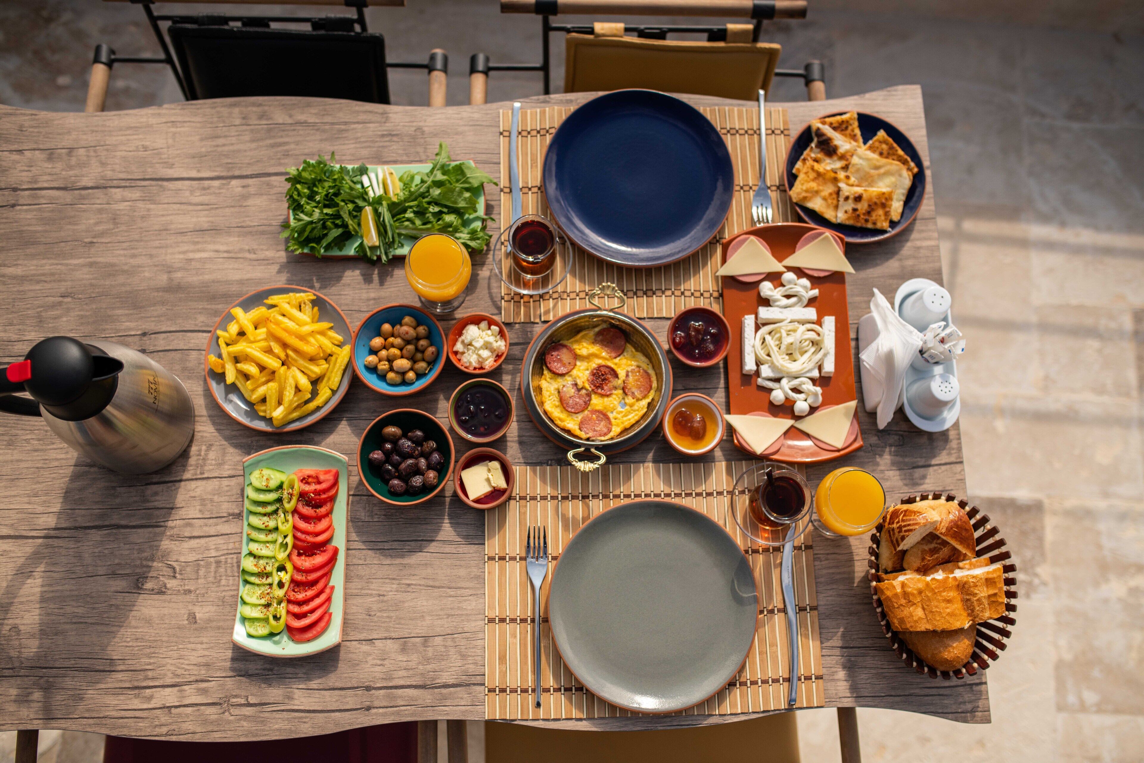 A breakfast table with various dishes, including eggs, bread, and fruits.