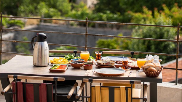 A table set for breakfast with a view of rocky formations and buildings in the background. - Ahiyan Hotel (Nevsehir)