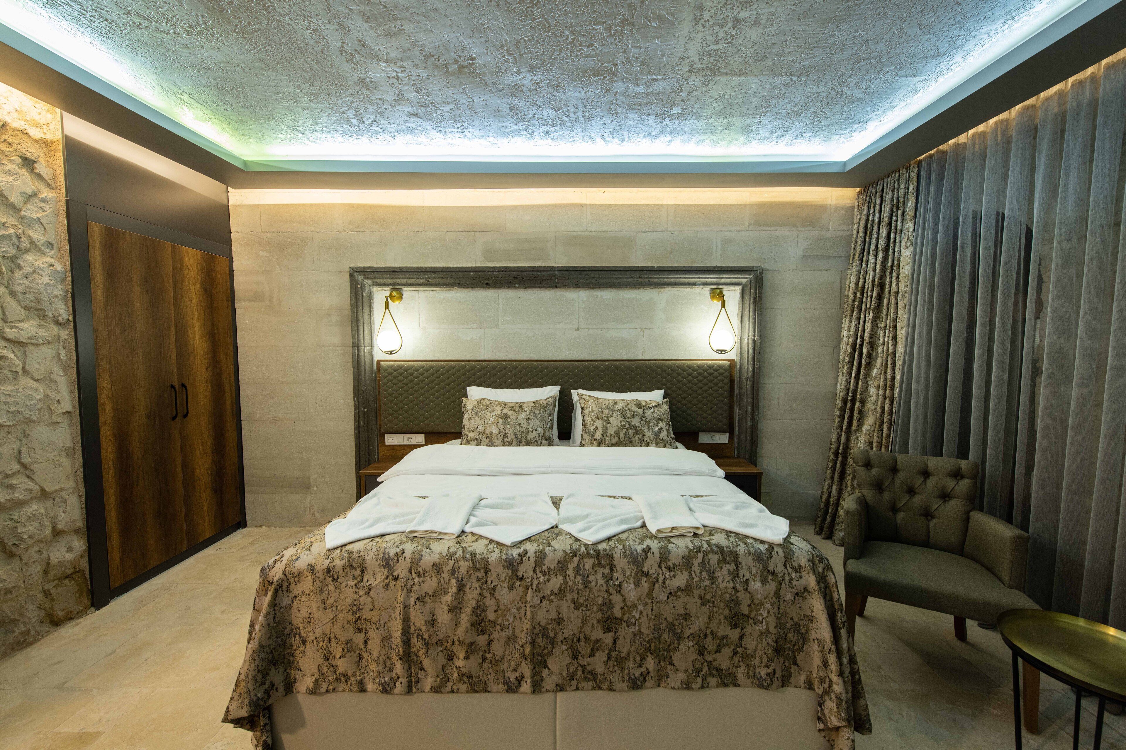 Un dormitorio moderno con una cama grande, un cabecero iluminado, una pared de piedra y una puerta de madera.