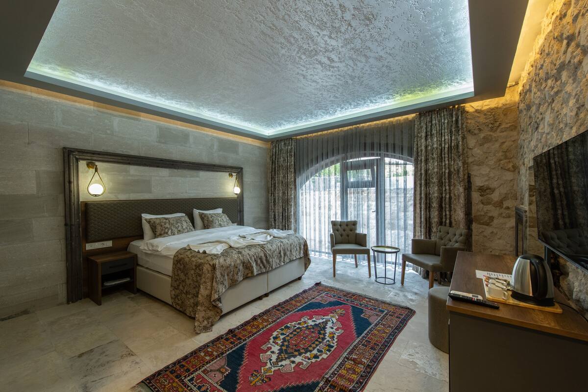 A bedroom with a large bed, a desk, a chair, and a fireplace.