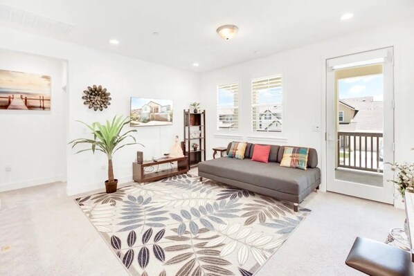 Relax in this stylish living room with a sofa, potted plant, and decorative wall piece.