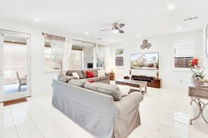 Relax in this stylish living room with a large sofa, flat-screen TV, and decorative wall piece.