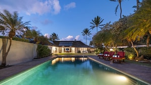 Une piscine avec des chaises longues et une maison en arrière-plan.