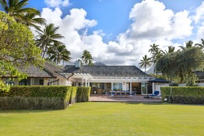 A resort with a covered outdoor seating area, palm trees, and a stone wall.