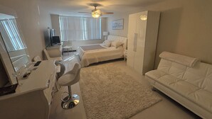 Une chambre d’hôtel comprenant un lit, un canapé, un bureau avec une chaise, une armoire et un ventilateur de plafond.