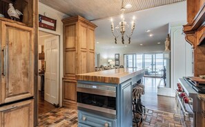 A kitchen with wooden cabinets, a built-in oven, a large island, and a view to the living area.