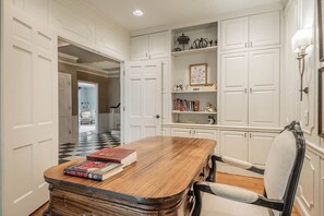 A room with a wooden table, a chair, and white cabinetry. - Spacious 5BR estate with Jacuzzi, pool, patio, and full kitchen. (Guntersville)