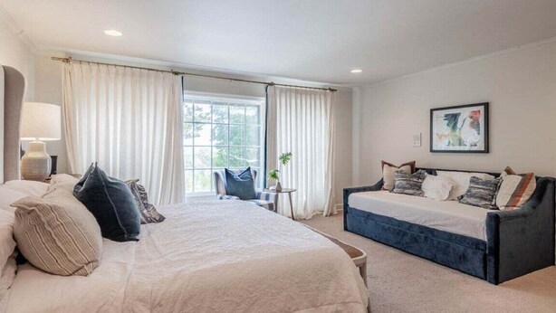 A hotel room with a bed, a sofa, a lamp, a plant, and a window with curtains. - Spacious 5BR estate with Jacuzzi, pool, patio, and full kitchen. (Guntersville)