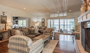 A spacious living room with a fireplace, a large window, and a view of the outdoors.