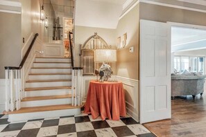 A staircase with a checkered floor, a round table with a tablecloth, and a bathtub in the background. - Spacious 5BR estate with Jacuzzi, pool, patio, and full kitchen. (Guntersville)