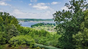 A lush green landscape with a view of a body of water and distant hills. - Spacious 5BR estate with Jacuzzi, pool, patio, and full kitchen. (Guntersville)