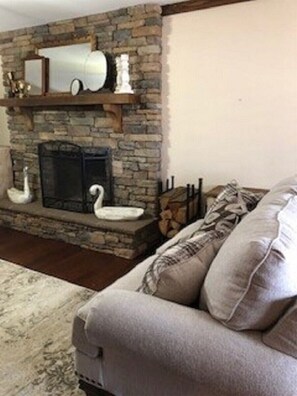 Una sala de estar con chimenea de piedra, un sofá y un plaid estampado.