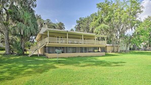 A two-story building with a balcony, surrounded by trees. - Waterfront Welaka Escape w/ Private Docks! (Welaka)